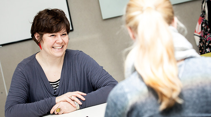 Staff member and student talking (sat opposite each other and smiling)