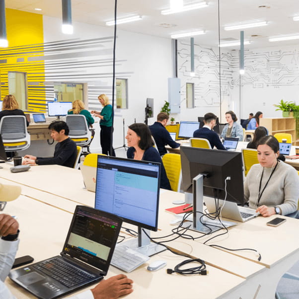 Graduates sitting at desks and using laptops/desktops in Launch Space.