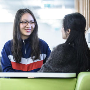 Two students having a conversation in a cafe.