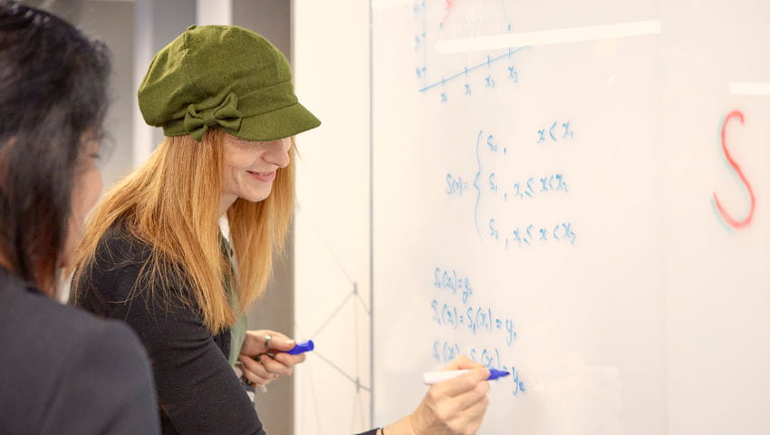 Students writing on the white board in the Maths Hub