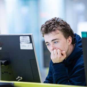 Student leaning on elbow looking at a PC