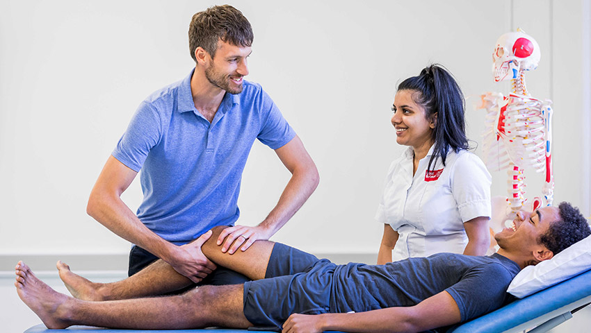 Physiotherapy lecturer demonstrating leg treatment to students