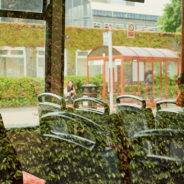 A bus stop through a window of a coach 