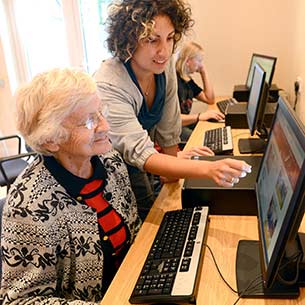 A volunteer helping an elderly woman to use a computer.