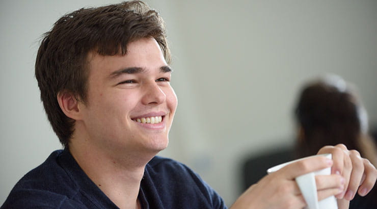 Smiling male student holding a mug