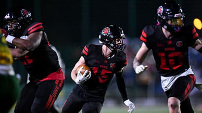 A UWE Bullets player on the pitch, leaning into his sprint with the ball in the middle of a game.