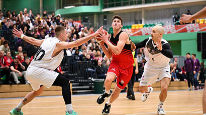 A UWE Jets basketball player springs forward with the ball mid game.
