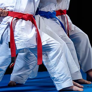 A line of three students in a karate pose on a blue mat.