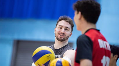 Two students laughing on the volleyball court at a MOVE session in the Centre for Sport.