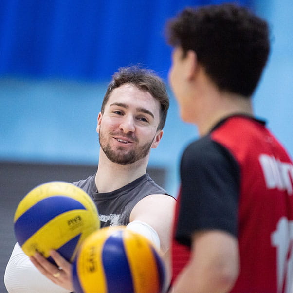 Two students laughing on the volleyball court in the Centre for Sport at UWE Bristol.