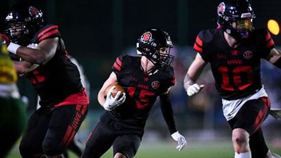 American football performance sport player running while clutching football.