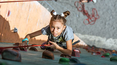 Child climbing up a climbing wall.