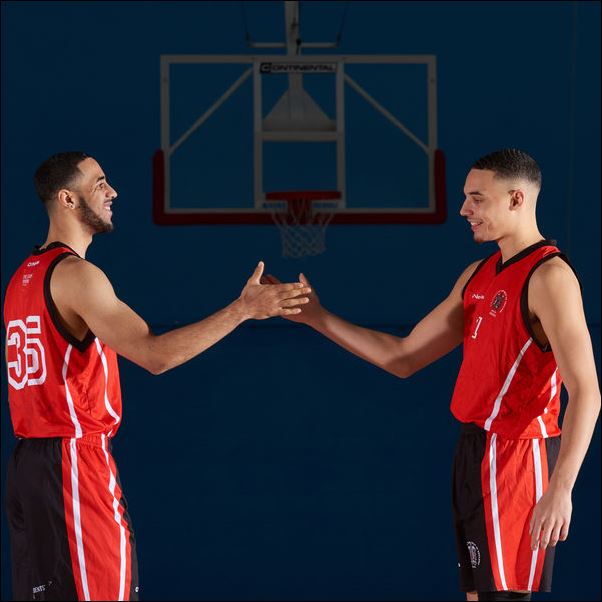 Two basketball players shaking hands on court.
