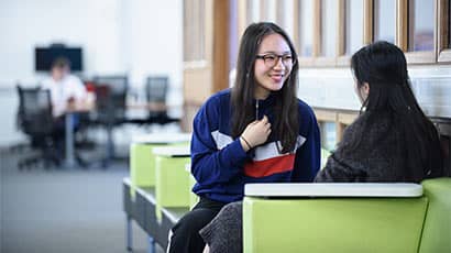 Two female students sat facing each other, chatting