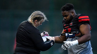 Performance Sport's sport therapist Emily tightening an athlete's glove.