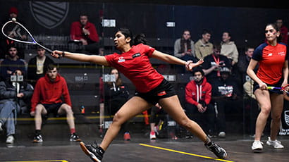 A UWE Bristol athelete reaching for the ball with her squash racket. 