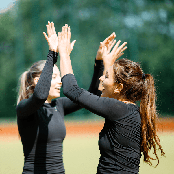 Two students high five each other while smiling.