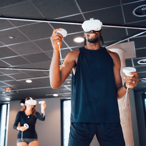 A man using the virtual reality headsets with a woman in the background