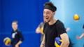 A student laughs while standing with a volleyball tucked under his arm during a MOVE session at the Centre for Sport. 