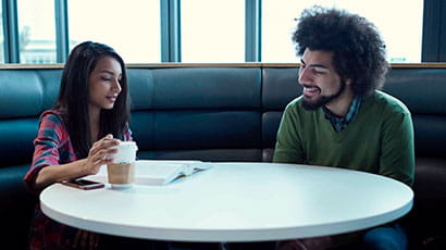 Two students having a conversation in a booth on campus
