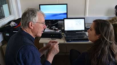 A volunteer talking to someone in front of a computer.