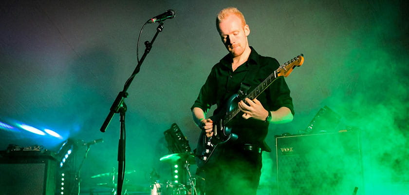 Ash Tucker playing the guitar on stage.