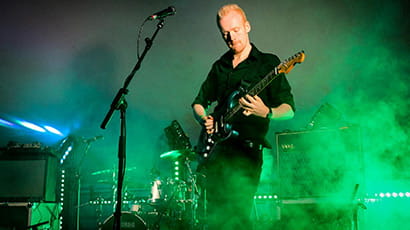 Ash Tucker playing the guitar on stage.