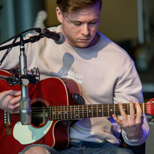 Person playing a guitar with a microphone in front of them.