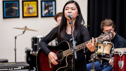 Person playing a guitar leading a band.