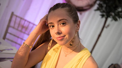 Young woman, Ellie in yellow top looking at camera with head leaning on her hand