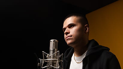 Young man standing in front of microphone with white T shirt and black hoody