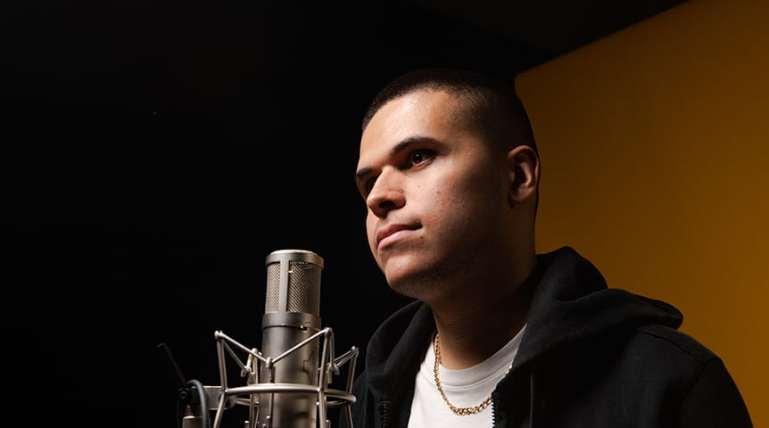 Young man standing in front of microphone with white T shirt and black hoody