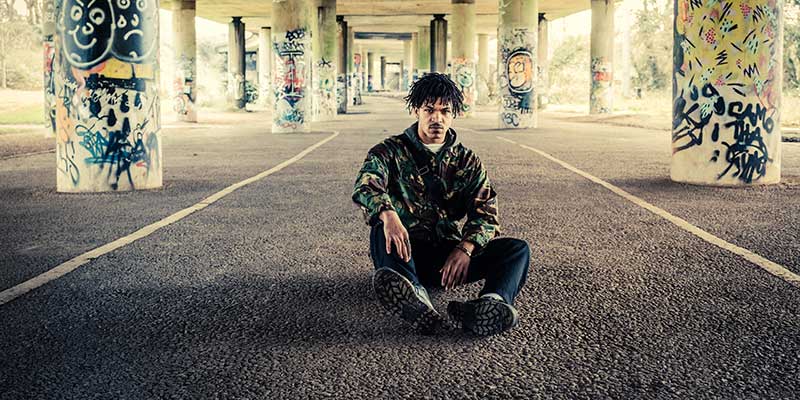 Profile of Lewis (Ibepuffy) sitting underneath a bridge