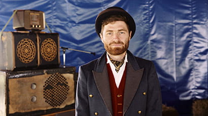 Portrait of Mike Fergie, aka Suitcase Sound System, standing in front of suitcases.