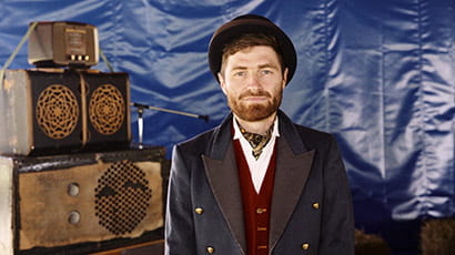 Portrait of Mike Fergie, aka Suitcase Sound System, standing in front of suitcases. Portrait of Mike Fergie, aka Suitcase Sound System, standing in front of suitcases.