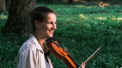 Laura Wilson playing a violin in a park.  Laura Wilson playing a violin in a park.
