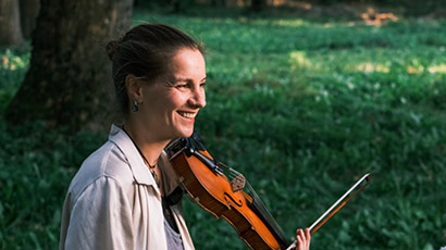 Laura Wilson playing a violin in a park. 