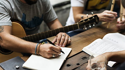 Closeup of someone holding a guitar while writing a song.