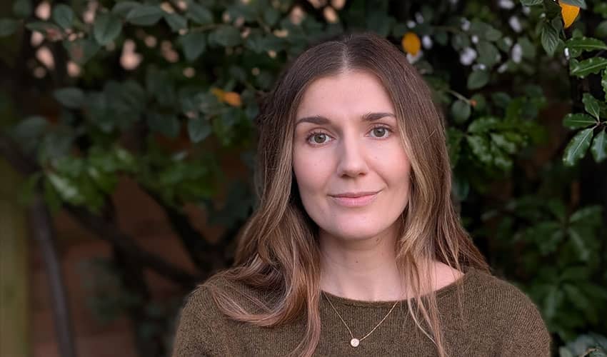 A head and shoulders image of a woman posing in front of a a green background