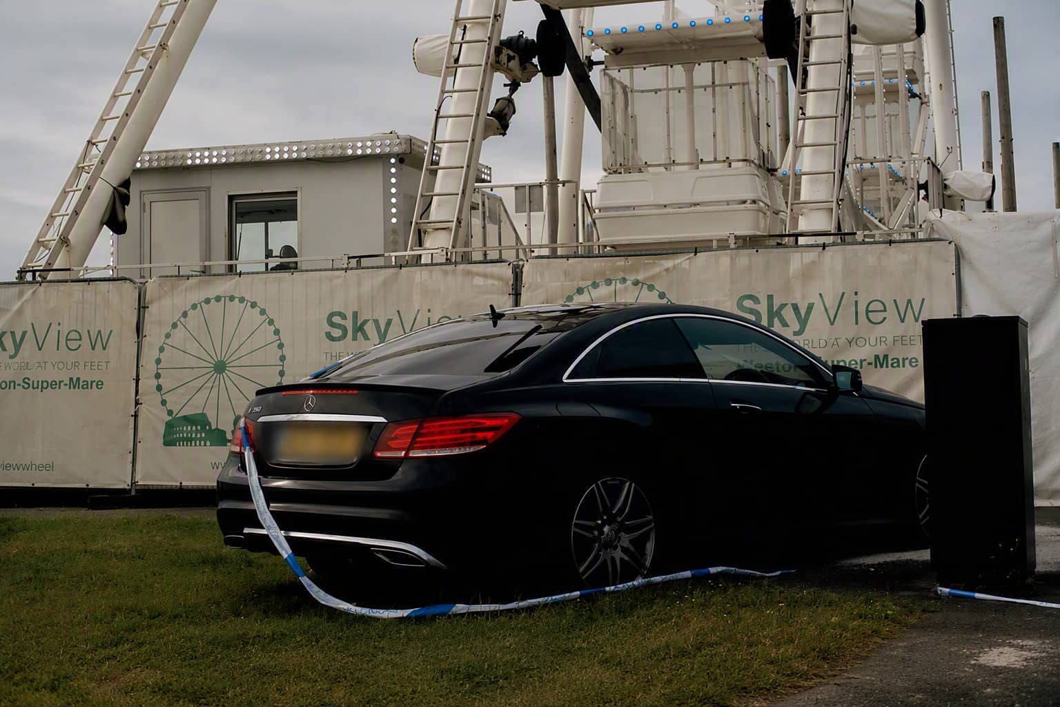A crashed car is pictured with police tape in front of the Ferris wheel. 