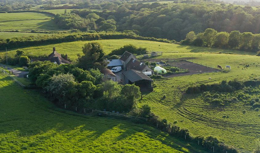A farm sits among fields in the English countryside.