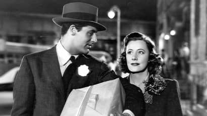 Two people walking at night, one holding a large paper-wrapped package.