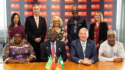 A group of people stood in front of a UWE Bristol branded banner in two rows.