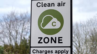 A traffic sign with a green and white logo for a clean air zone