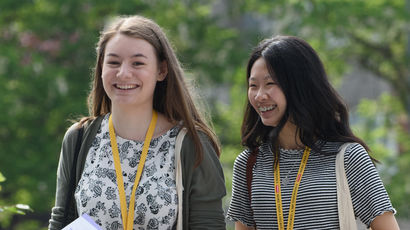 Two female students walking along smiling.