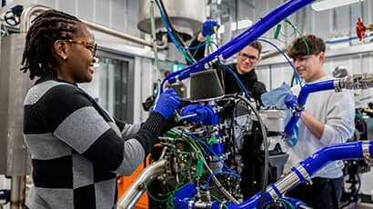 Three young people stood working with technical engineering equipment in a studio