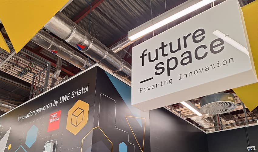 A black wall with graphic design across it next to a hanging sign saying Future Space