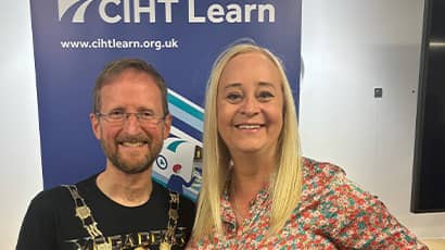 Glenn Lyons and Karen McShane, CIHT Past President, smile in front of a CIHT advertising banner 