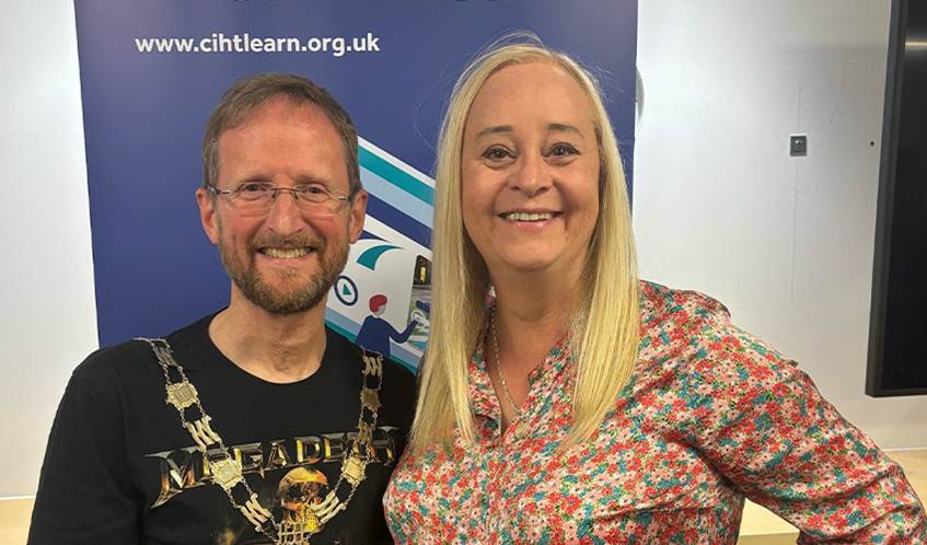 Glenn Lyons and Karen McShane, CIHT Past President, smile in front of a CIHT advertising banner