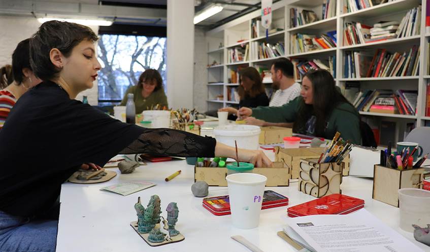A group of students take part in a workshop, creating clay and wax models.